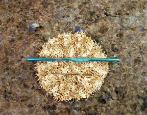 Scrubbers Using "Scrubby" Yarn - finished scrubby with a hook and the darning needle lying across it