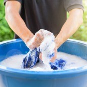 A blue basin with soapy clothing.