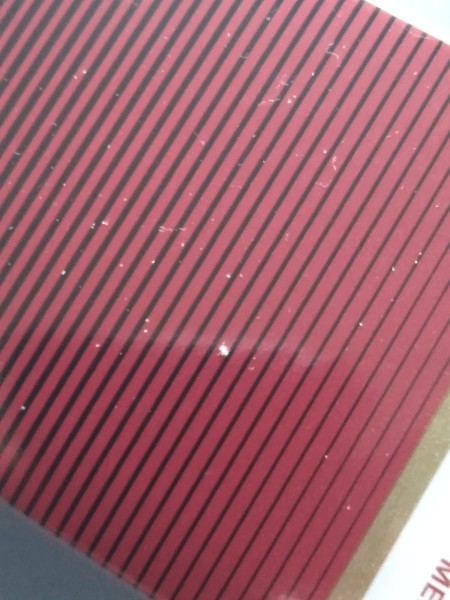 Small flecks of white on a red striped surface.