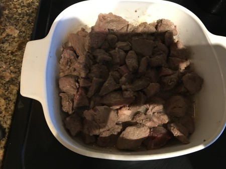 A casserole pan with small pieces of cooked beef.