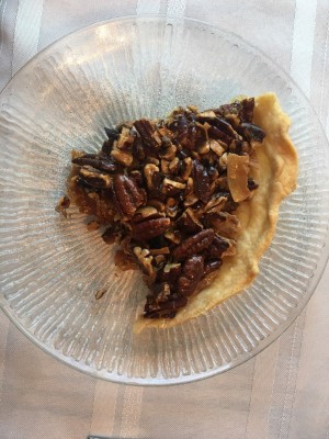 A slice of triple nut tart on a plate.