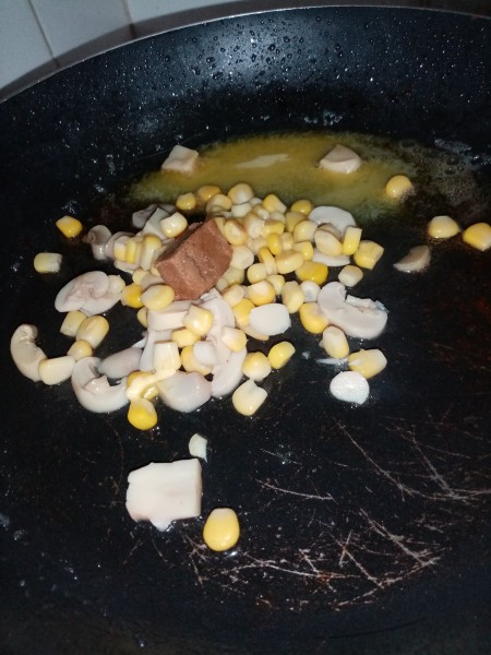 Corn and mushroom pieces in a pan.