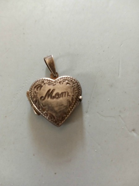 A metal locket that says "Mom".