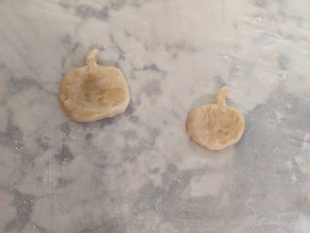 Two pumpkin shapes cut from piecrust dough.