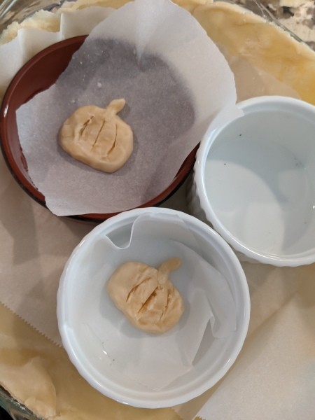 Two small piecrust pumpkin decorations, ready for baking.