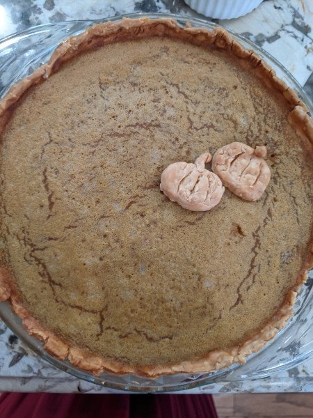 A pumpkin pie with two small piecrust pumpkin decorations.