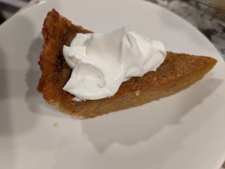 A slice of pumpkin pie with whipped cream.