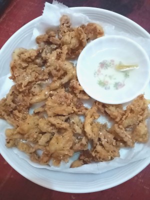 A finished plate of mushroom chicharon served with spicy vinegar.