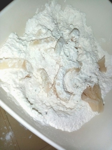 Tossing mushroom pieces in seasoned flour.