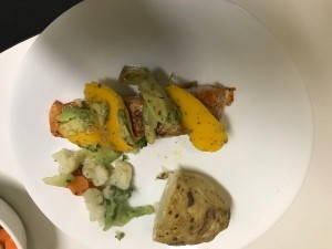 A plate of salmon with avocado mango salsa.