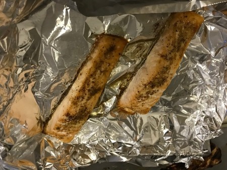 Two cooked salmon filets on aluminum foil.