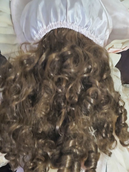 Back of doll's head with white bonnet.