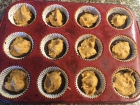 A muffin tray with spoonfuls of peanut butter filling.