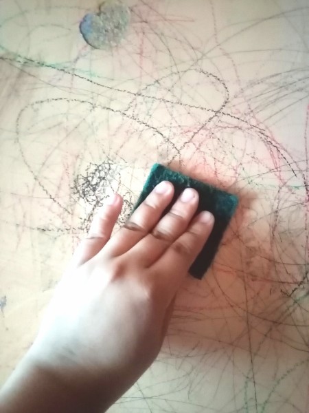 Using a scrubby pad on a scribbled-on wall.