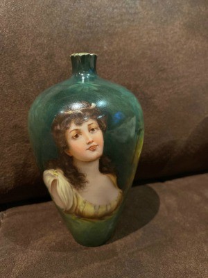 A green porcelain vase with a woman painted on it.