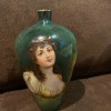 A green porcelain vase with a woman painted on it.