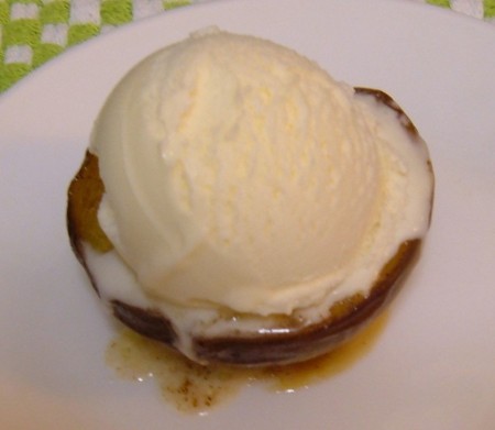 The half peach served with a scoop of vanilla ice cream.