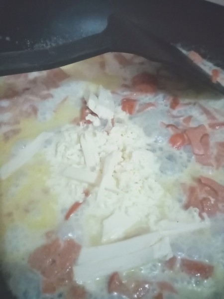 Adding cheese to the sauce.