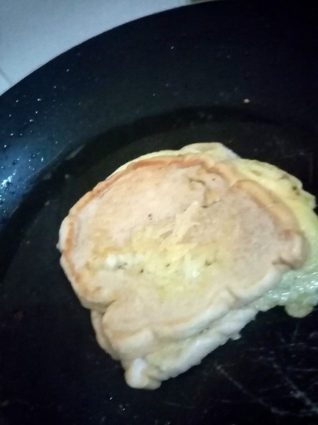 Flipping the sandwich in the pan.