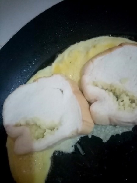 Adding bread to the egg pan.