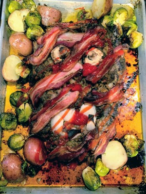 A creepy zombie meatloaf with roasted vegetables around it.