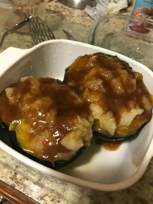 A casserole dish with halved acorn squash filled with an apple mixture.