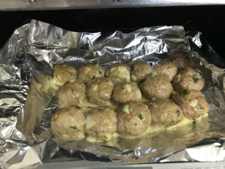 Several cooked meatballs on aluminum foil.