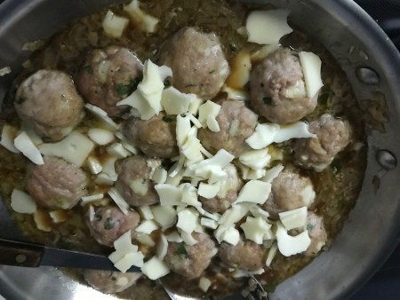 Adding cheese to the French onion meatballs.