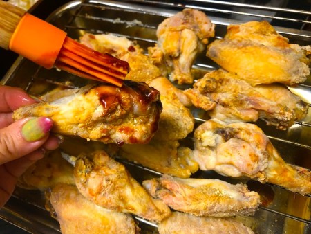 Brushing the sauce onto the wings.
