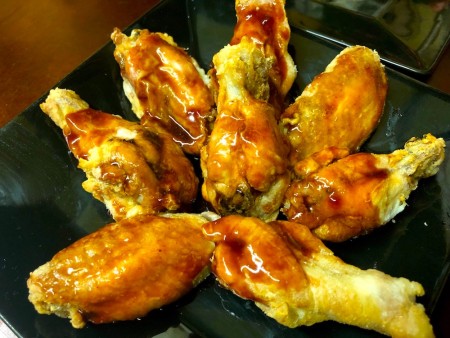 A plate of crispy bat wings with sauce.