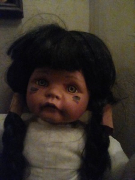 A porcelain doll with marking under her eyes and long dark braids.