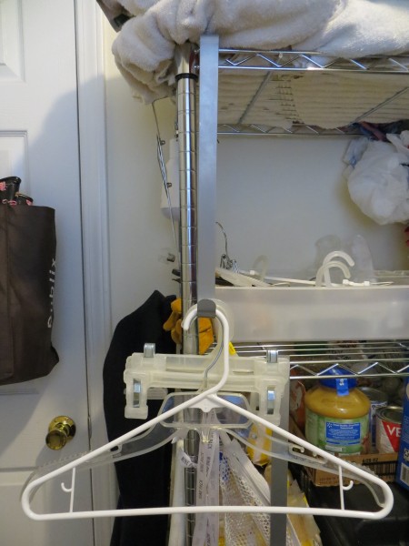 A wreath hanger holding up laundry hangers on a shelf.