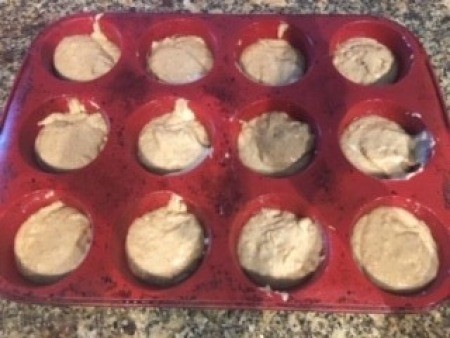 Adding the muffin batter into a muffin tin.