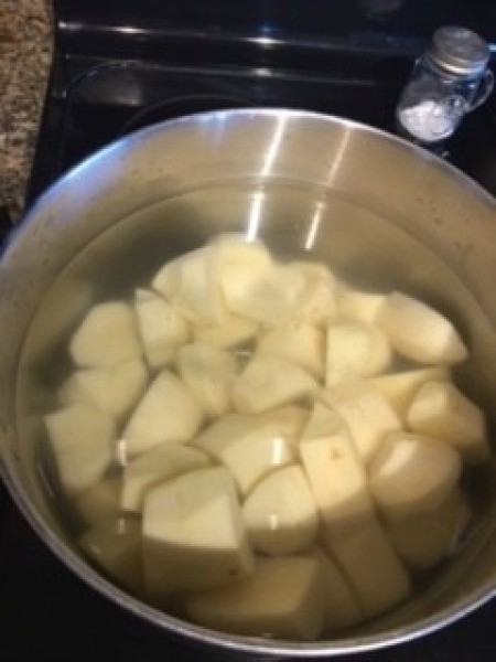 A pan of cut up potatoes in water.