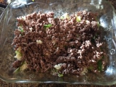 Adding ground beef and other ingredients to a baking pan.