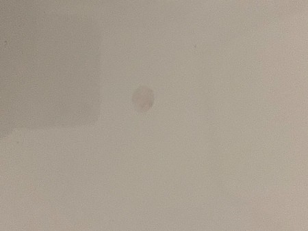 A mark on a white glossy surface.