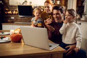 Family of 4 with two young children having a video chat on a computer.