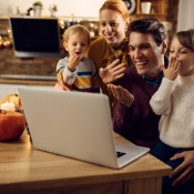 Family of 4 with two young children having a video chat on a computer.