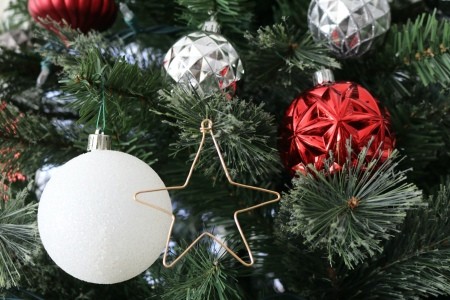 A bent wire ornament in the shape of a star, hanging on a Christmas tree.