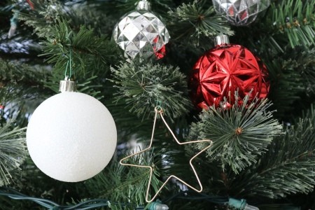 A bent wire ornament in the shape of a star, hanging on a Christmas tree.