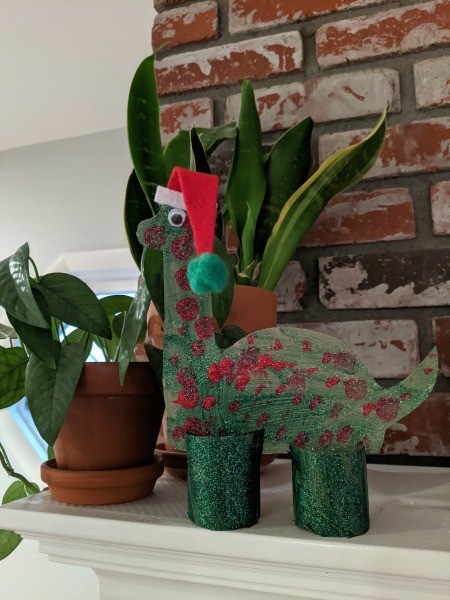 Christmas Dino Decoration - finished dino decoration on the mantel next to two potted plants