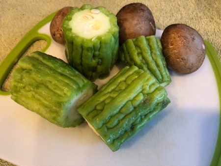 Chinese bitter melon and mushrooms on a cutting board.