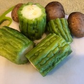 Chinese bitter melon and mushrooms on a cutting board.