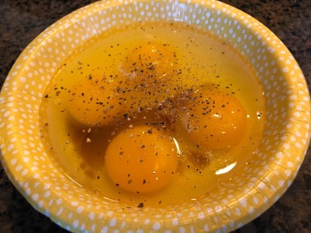 Eggs and spices in a paper bowl.