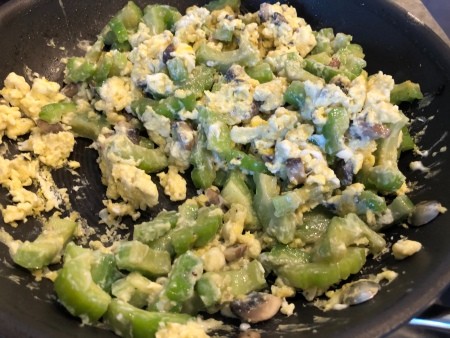 Cooking the vegetables with scrambled eggs in a frying pan.