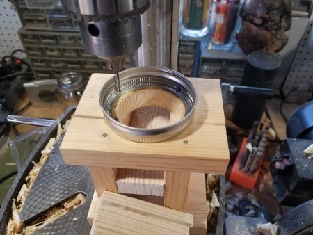 Drilling a hole in a Mason jar ring.
