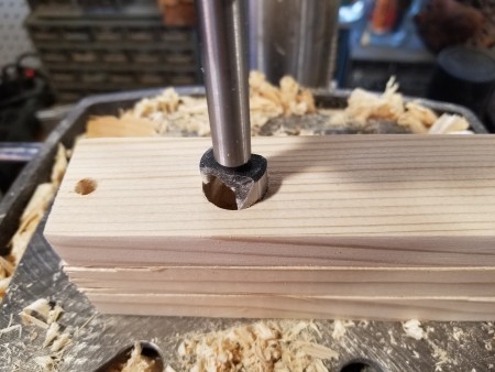 Drilling a large hole in a stack of boards.