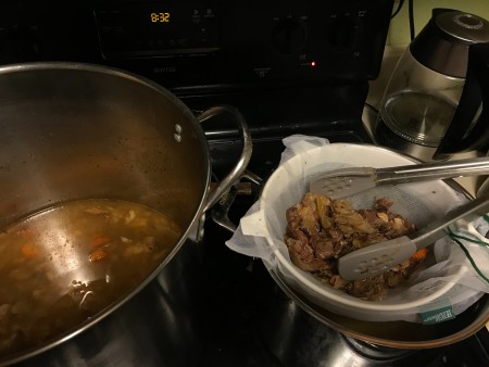 Removing the bones and veggies from the broth.