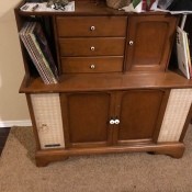 An old record player cabinet with scratches on the speaker cover.