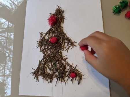 Adding pom poms to the tree as decorations.